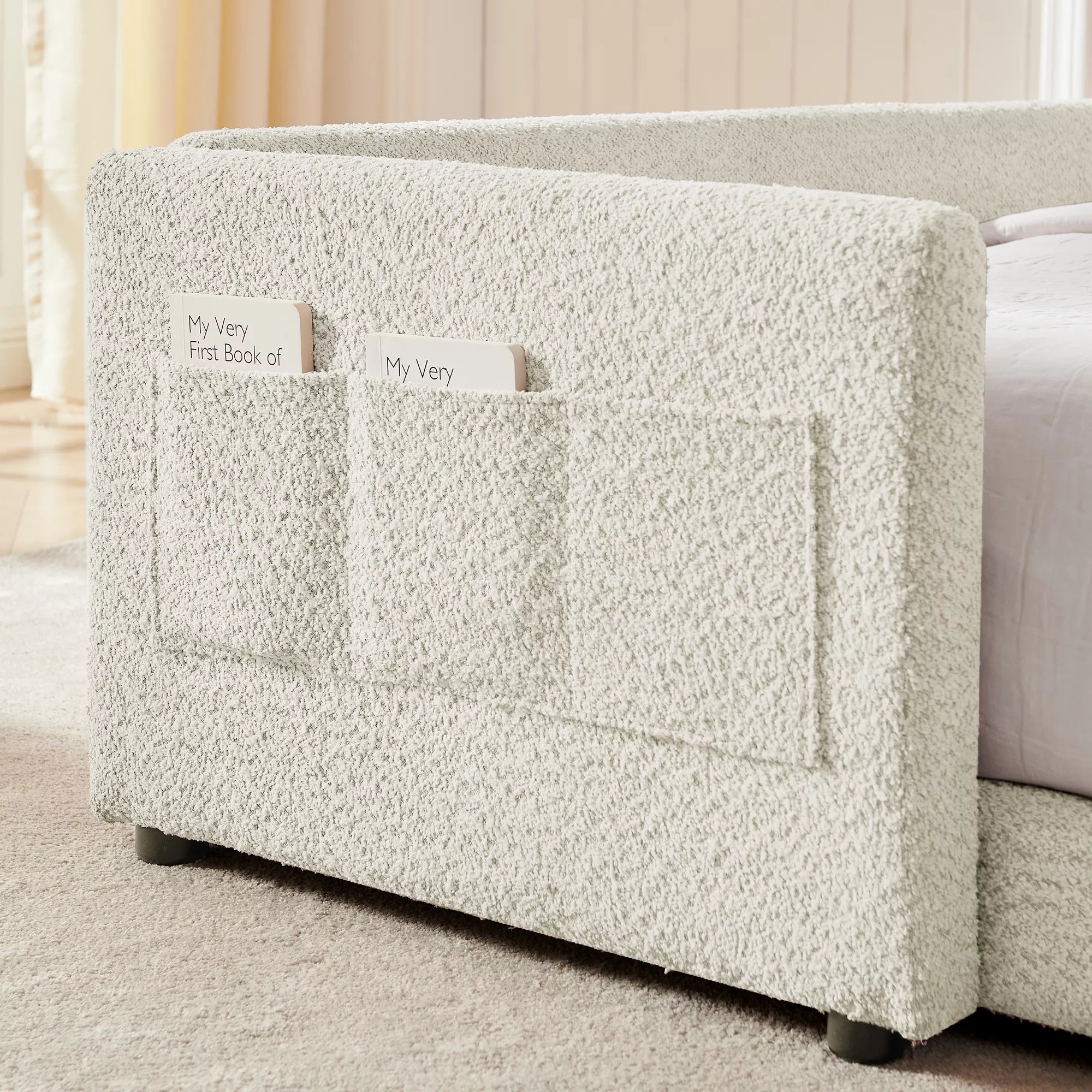 Side storage pockets on boucle kids bed frame, fabric book pockets for storing children’s books and small items, cream white