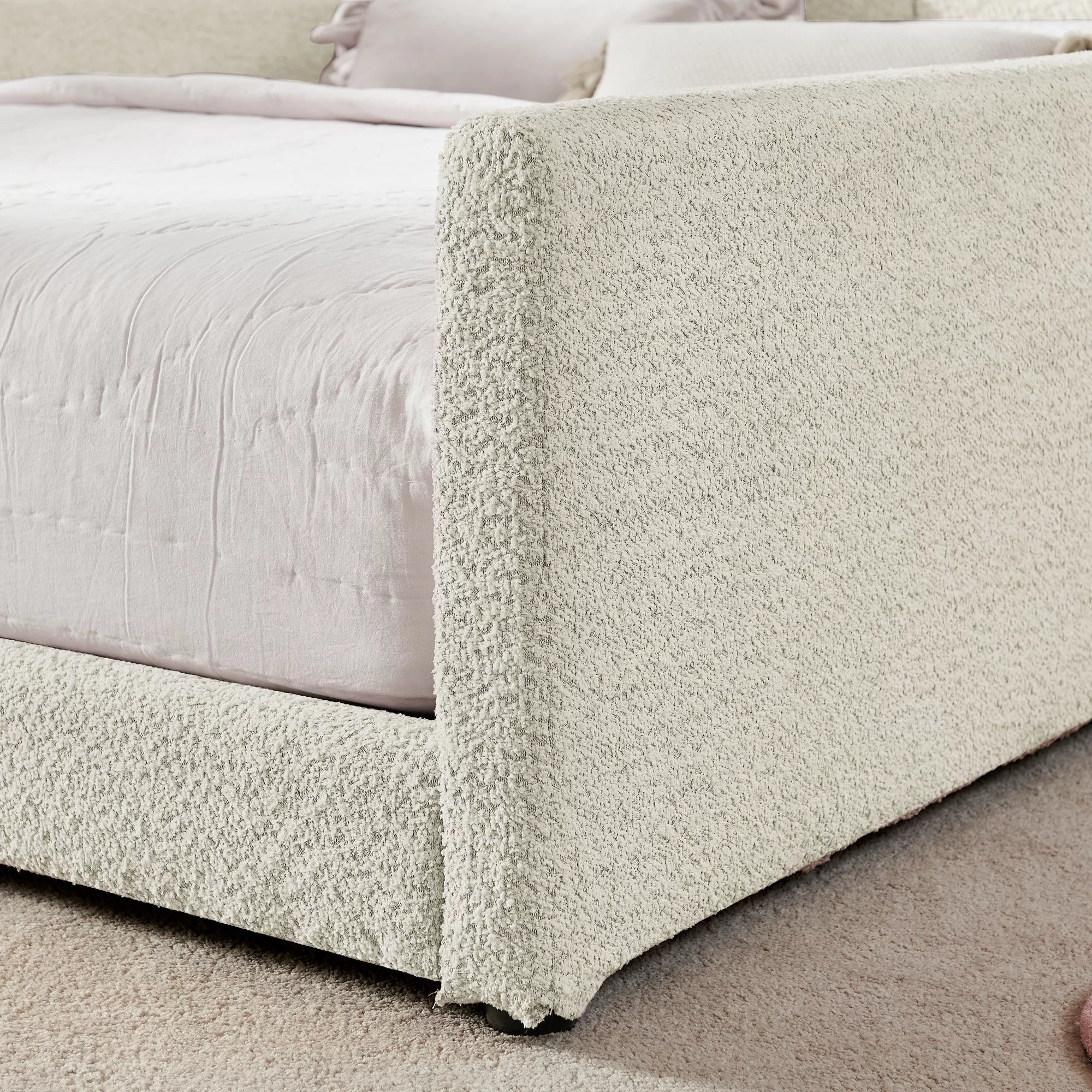 Teddy boucle fabric close‑up, upholstered side safety rail of full size kids bed frame, cream white texture view