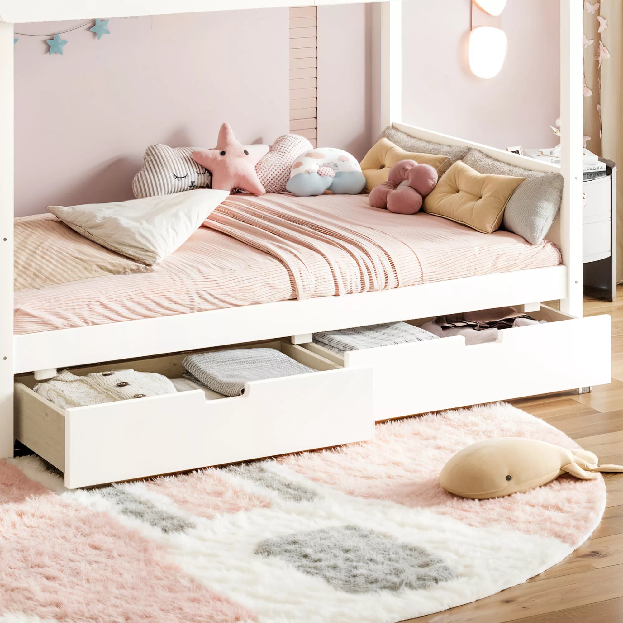 White kids bunk bed with two storage drawers styled in a pink bedroom