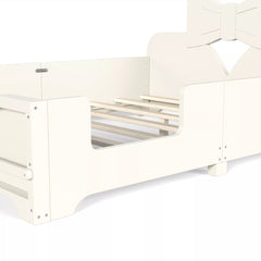 Close‑up view of white kids bed frame showing wooden slats, safety side rails and bow headboard structure