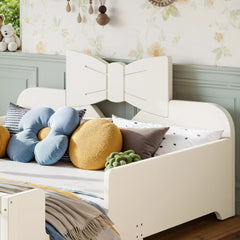 Close‑up of decorative bow headboard on white wooden kids bed with colorful throw pillows in bedroom