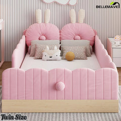 Pink upholstered platform bed with bunny ear pillows in a child's bedroom