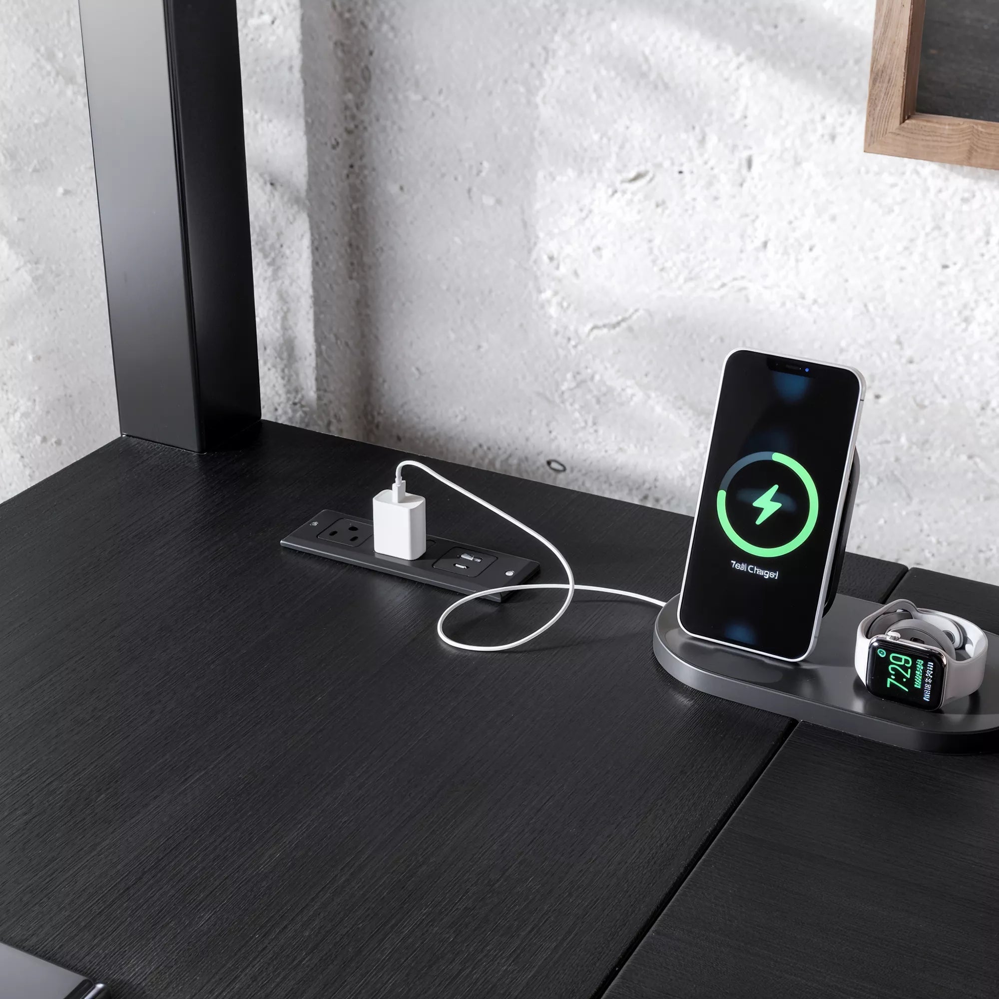 Close-up of a phone and charging accessories displayed on the black desktop
