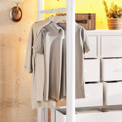 Hanging clothes beside fabric storage drawers under a white metal loft bed