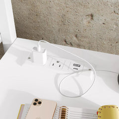 Close-up of the desk power panel beside a phone and notebook