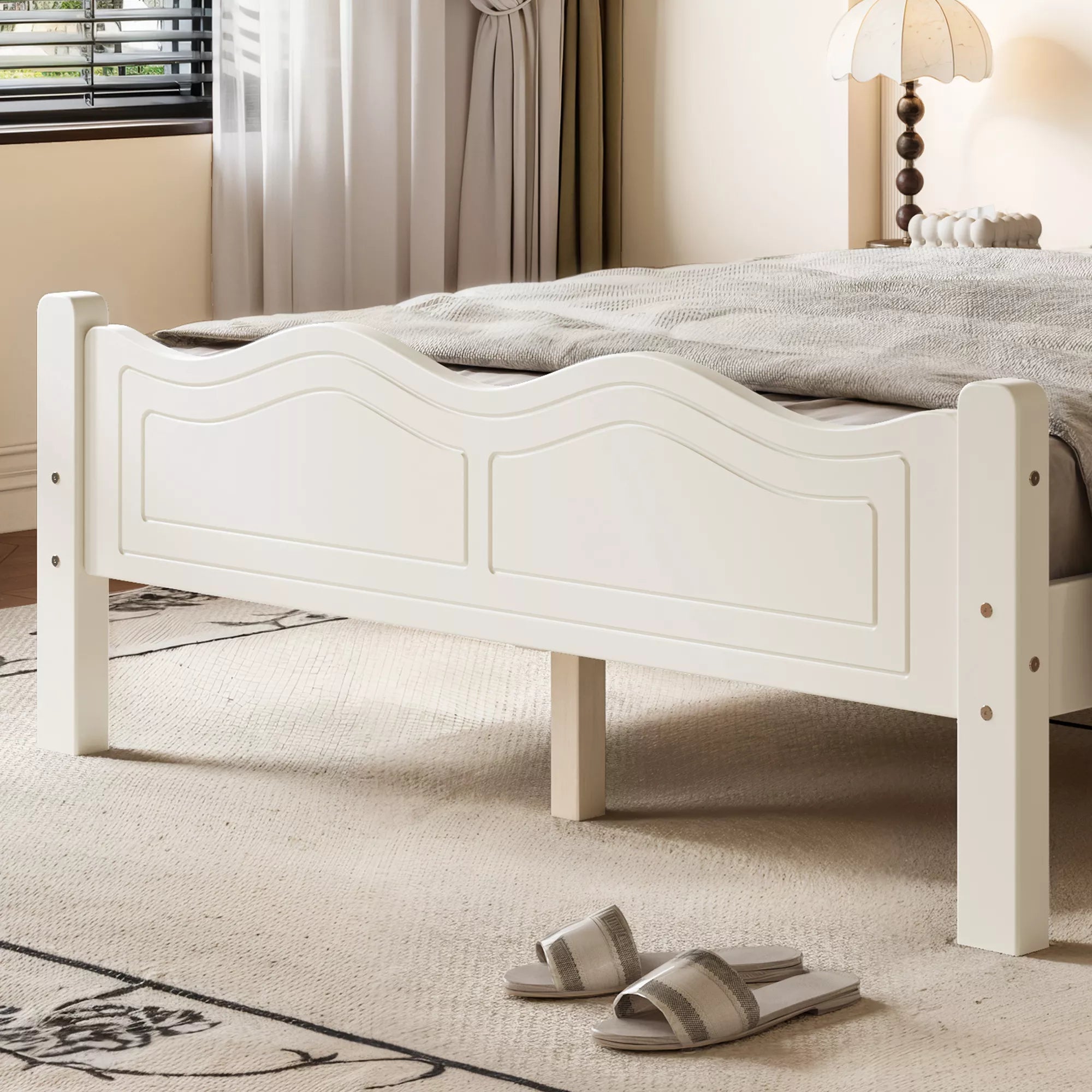 Close-up of the curved footboard panel on a white butterfly bed